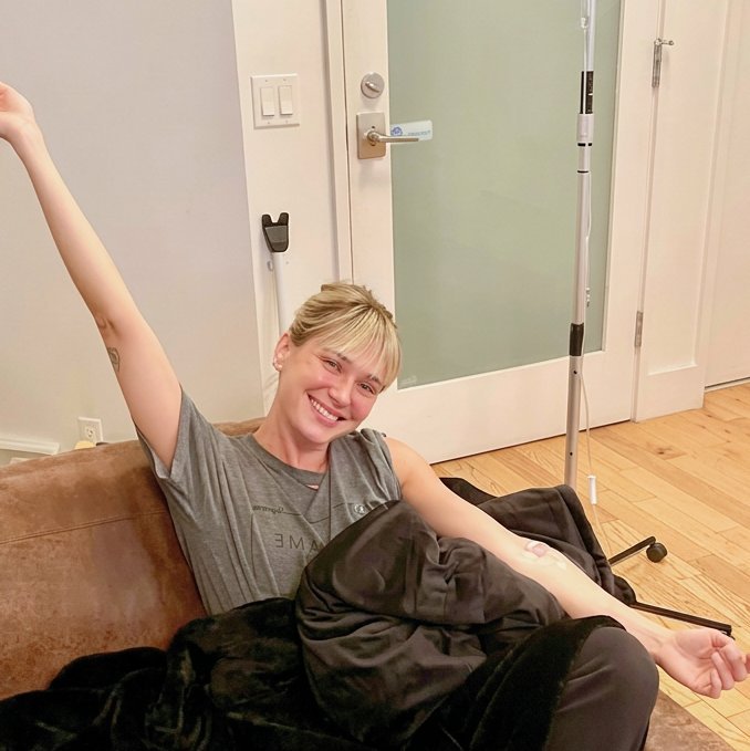 Smiling patient stretching on a sofa during an IV drip